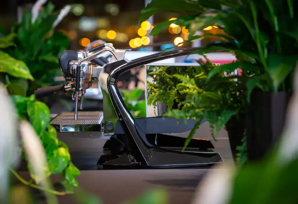 Slayer Steam LP commercial espresso machine surrounded by tropical plants in a café